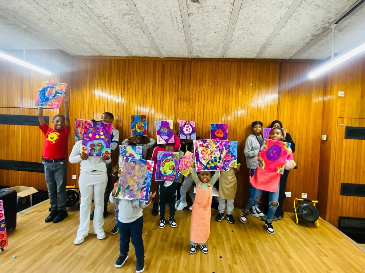 Children holding up their paintings at a SickleFES art workshop